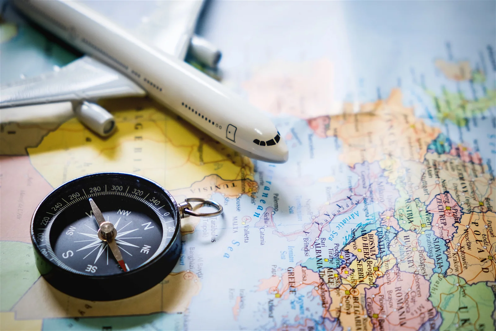 selective-focus-miniature-tourist-compass-map-with-plastic-toy-airplane-abstract-background-travel-c