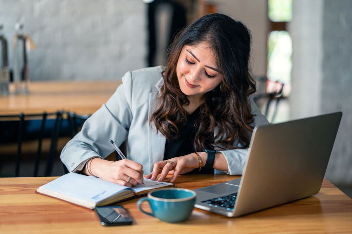 Devices_in_Use_Laptop_person_at_coffee_shop_writing_in_notebook_with_laptop_-gettyperp-